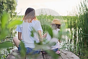 Children resting near the water on sunny summer day, back view