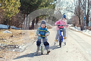 Children ride a bicycle and a runbike along the village road