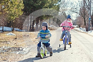 Children ride a bicycle and a runbike along the village road