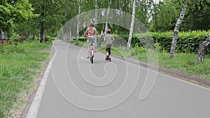 Children ride bikes and scooter in the park