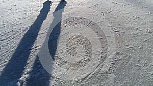 Children ride in a city park on an ice rink. Feet skater while skating on ice. The low winter sun weakly illuminates the