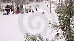 Children ride fast downhill on tubing from the slope in defocus.