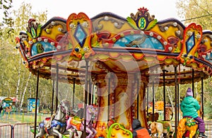 Children ride on the horses on the colorful carousel in the Park