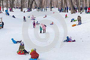 Children ride in a park on a snow hill on a sled