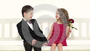 Children ride a swing and a little boy kisses the girl on the cheek. White background. Slow motion