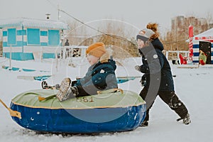 Children ride a tubing. Outdoor winter games for the whole family. Happy children in winter play outside. cool soft sleds.