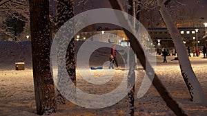 Children riding down a hill in winter in a city park