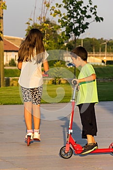 Children riding kick scooter in summer day