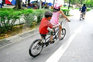 Children riding on a tandem bike.