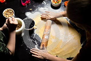 Children roll out the dough to make birthday cookies. Kitchen preparations. Joint activities in the family