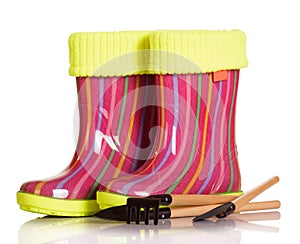 Children rubber boots with fabric inset, shovel and rake isolated.