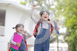 Children with rucksacks jumping in the park near school. Pupils with books and backpacks outdoors
