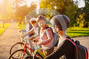 Children with rucksacks riding on bikes in the park near school