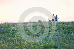 Children run across the field in summer among wildflowers, a sense of freedom, a happy childhood surrounded by nature, hiking,