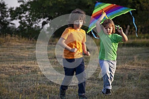 Children run with kite on summer sunset meadow. playing outdoors