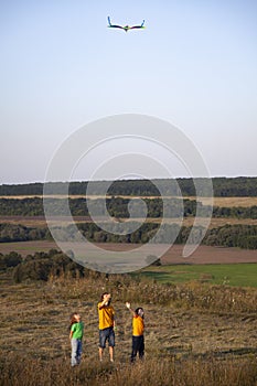 Children run playing kite on summer meadow