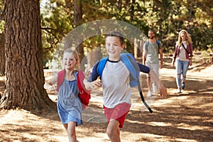 Children Running Ahead Of Parents On Family Hiking Adventure