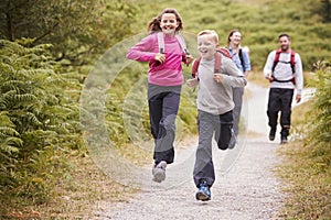Children running ahead of parents, walking on a country path during a family camping trip, front view, close up