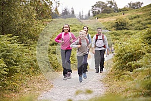 Children running ahead of parents walking on a country path during a family camping trip, selective focus