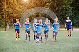 Children running and kicking soccer ball on children football training session