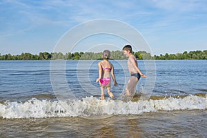 Children are running on water on a sunny day.  The  opening  of  the beach  season