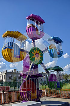 Children`s attraction is quarantined due to Covid-19. Colorful ferris wheel in amusement park on blue sky background. Close-up.