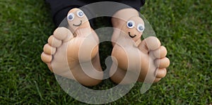 Children\'s bare feet on the grass with painted faces on their big toes. cheerful childhood
