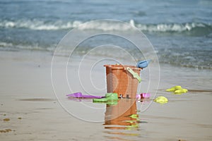 Children`s beach toys and orange bucket on summer tropical sand beach with blue sea