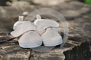 Children\'s beige denim sports shoes for girls, stands on a wooden stump. Close up view