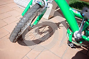 Children`s bicycle wheel and its shadow on the paving stones. Carved shadow from the spokes of a bicycle wheel