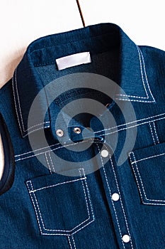 Children`s blue denim dress closeup, details. Pockets, stitching, metal buttons or rivets and collar. Jeans texture, denim jacket