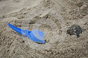 Children`s blue shovel lies on the sea coast. The shovel is lying on the sand. Space for text. Vacation on the ocean coast.