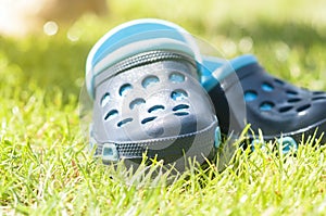 Children`s blue slippers on the green grass in the garden, shoes for children, beach fashion for kids, a concept of