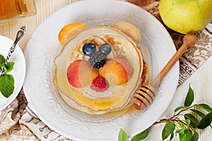 Children's breakfast pancakes smiling face of the baby teddy bear strawberry blueberry and apricot, cute food, honey