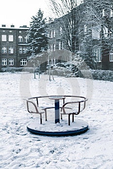 children\'s carousel covered with snow on the playground in winter
