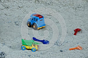 Children`s colored plastic toys lie on the sand in the sandbox