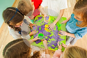Children`s creativity with color kinetic sand top view