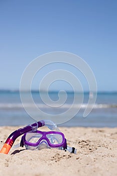 children's diving mask on the sand at the beach