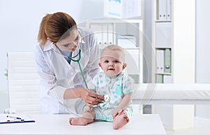 Children`s doctor examining baby with stethoscope in hospital.