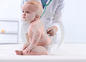 Children`s doctor examining baby with stethoscope in hospital.