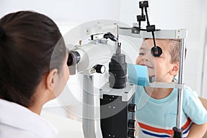 Children`s doctor examining little boy with ophthalmic equipment