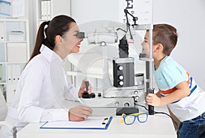 Children`s doctor examining little boy with ophthalmic equipment