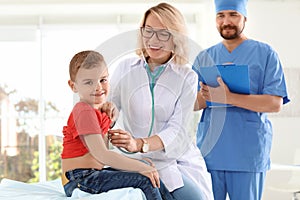 Children`s doctor examining little boy with stethoscope