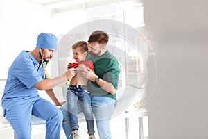 Children`s doctor examining little boy with stethoscope in hospital