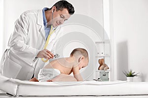 Children`s doctor examining little boy with stethoscope in hospital.