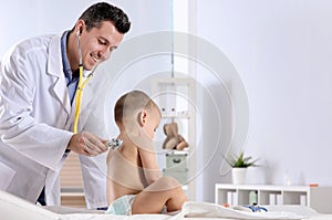 Children`s doctor examining little boy with stethoscope in hospital.