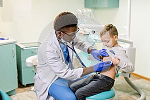 Children`s doctor examining little boy with stethoscope in hospital