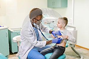 Children`s doctor examining little boy with stethoscope in hospital