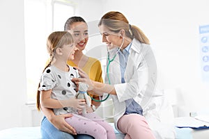 Children`s doctor examining little girl near parent