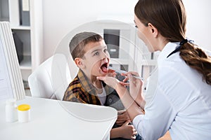 Children`s doctor examining patient`s throat in clinic